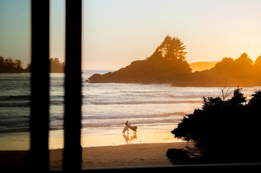 Surfers at sunset on Cox Bay beach in Tofino, a perfect coastal getaway from Vancouver.